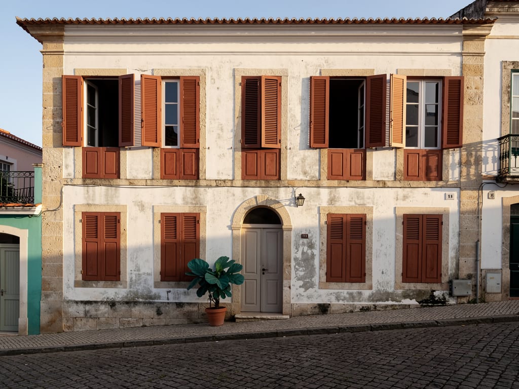 A restored colonial townhouse in Ribeira with terracotta shutters on a quiet cobbled street